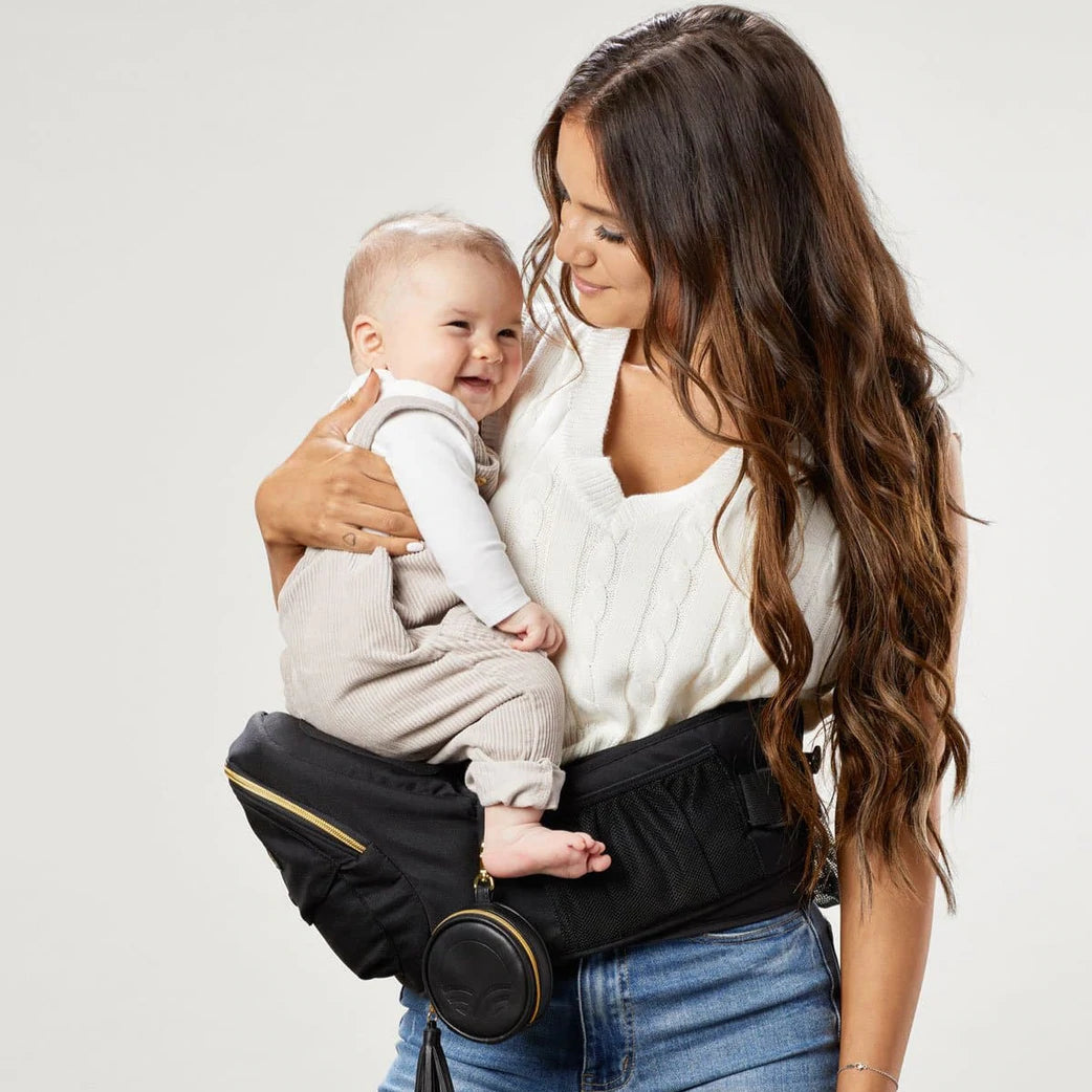 Tush baby with a baby on the tush baby with a mother carrying him. Tush baby is black and gold.