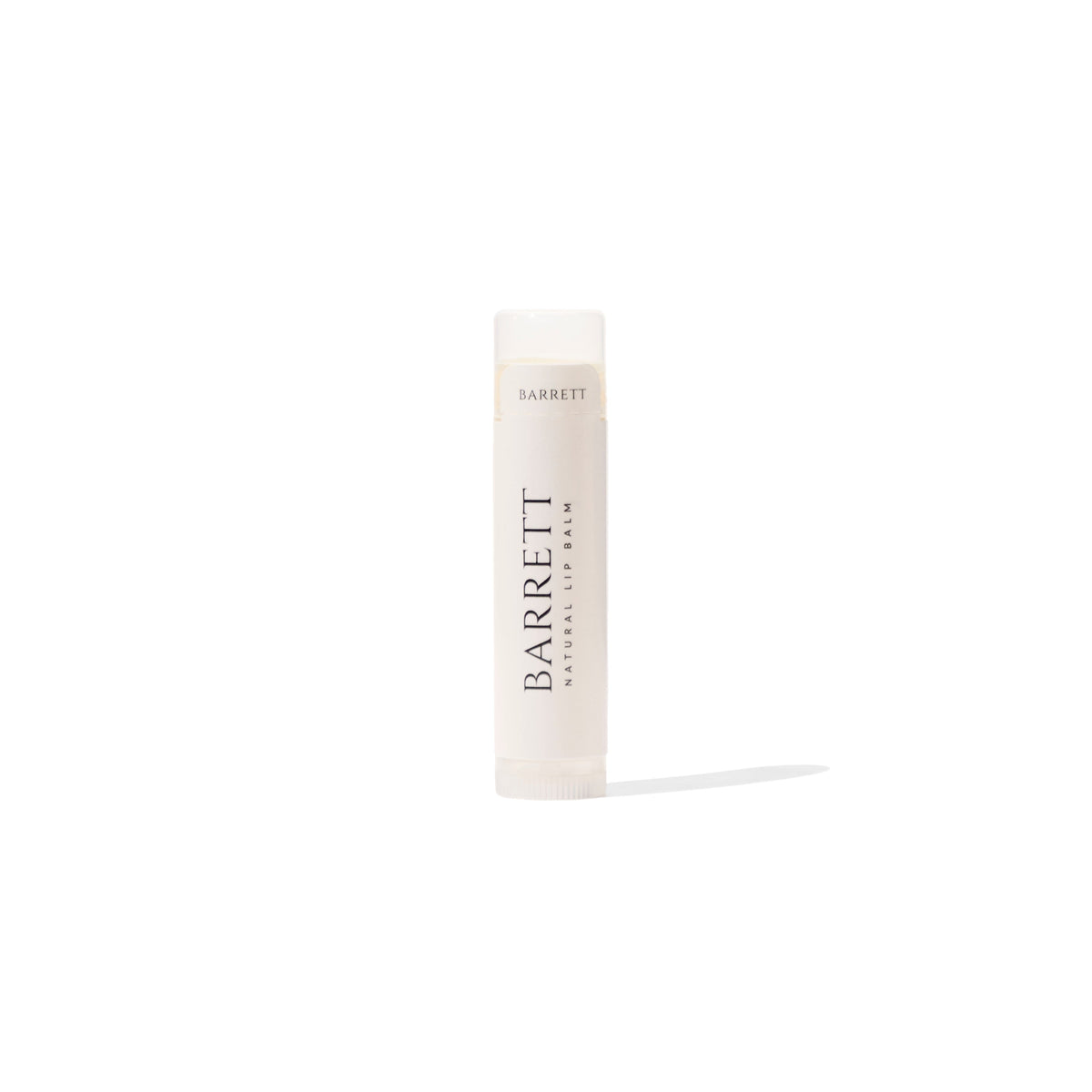 A stick of natural lip balm in a white twist-up tube with minimalistic design, labeled 'BARRETT'. Beef Tallow Lip Balm