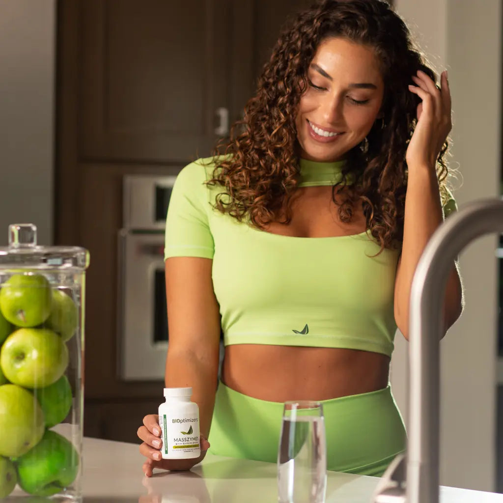 Woman taking Masszymes in green workout outfit
