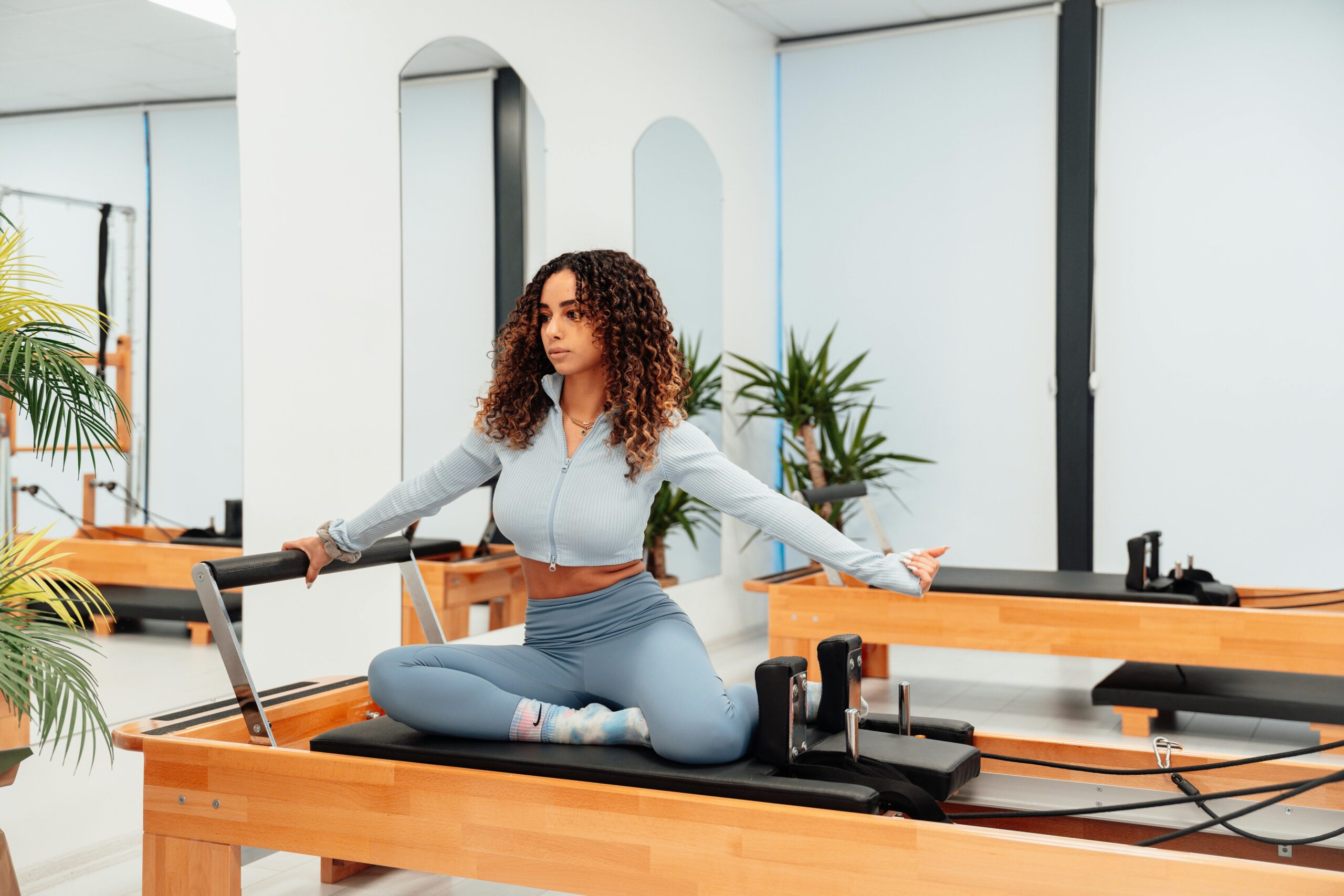 Woman on a pilates reformer doing a pilates move.